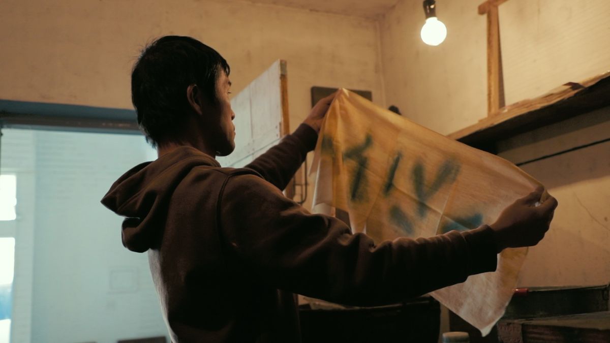 佐渡勝行氏が手ぬぐいを見る様子