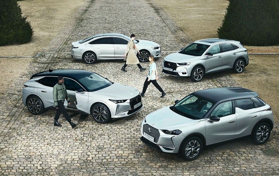 ４台の車の間をエココンシャスなコレクションを着た３人のモデルが行き交う