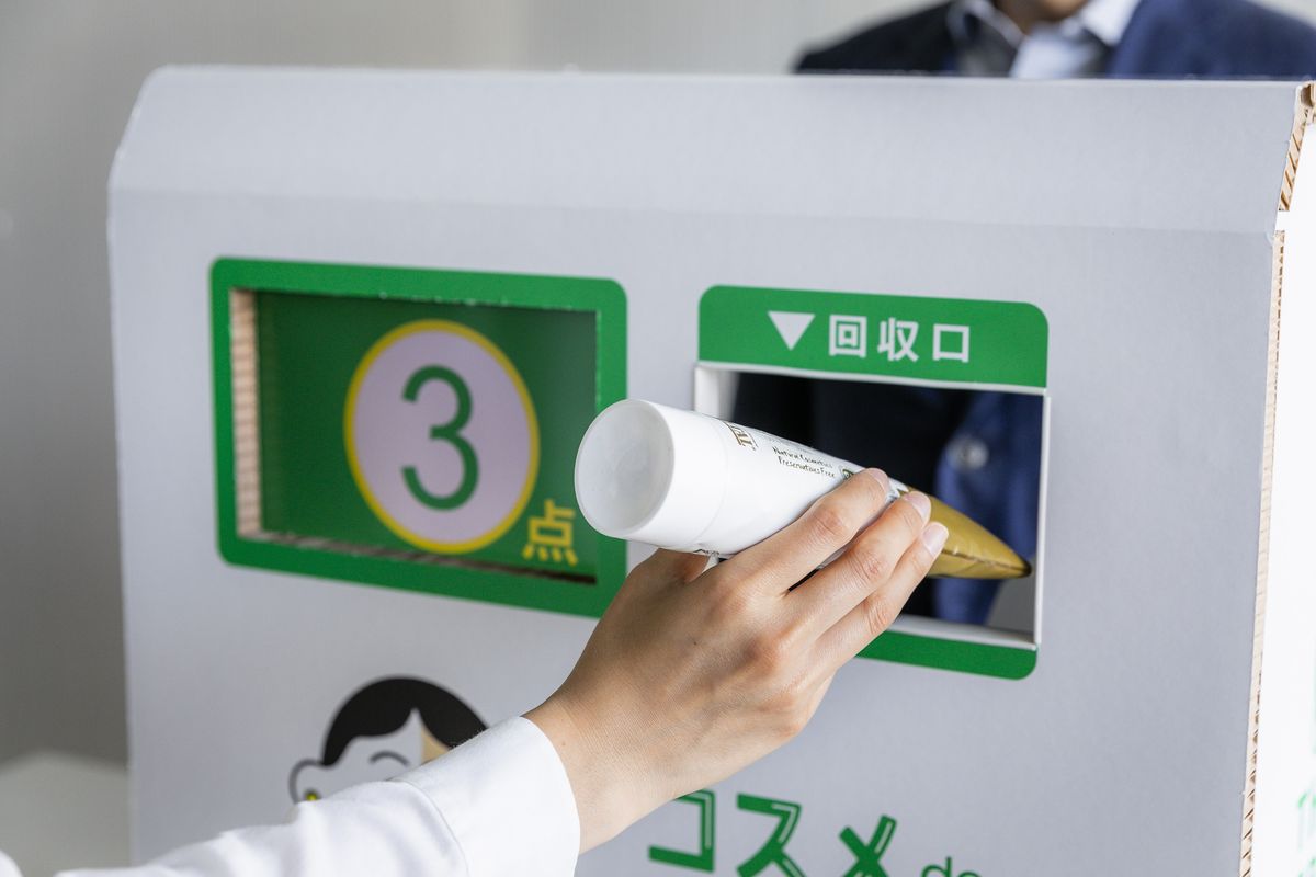 回収ボックスに化粧品を入れる手