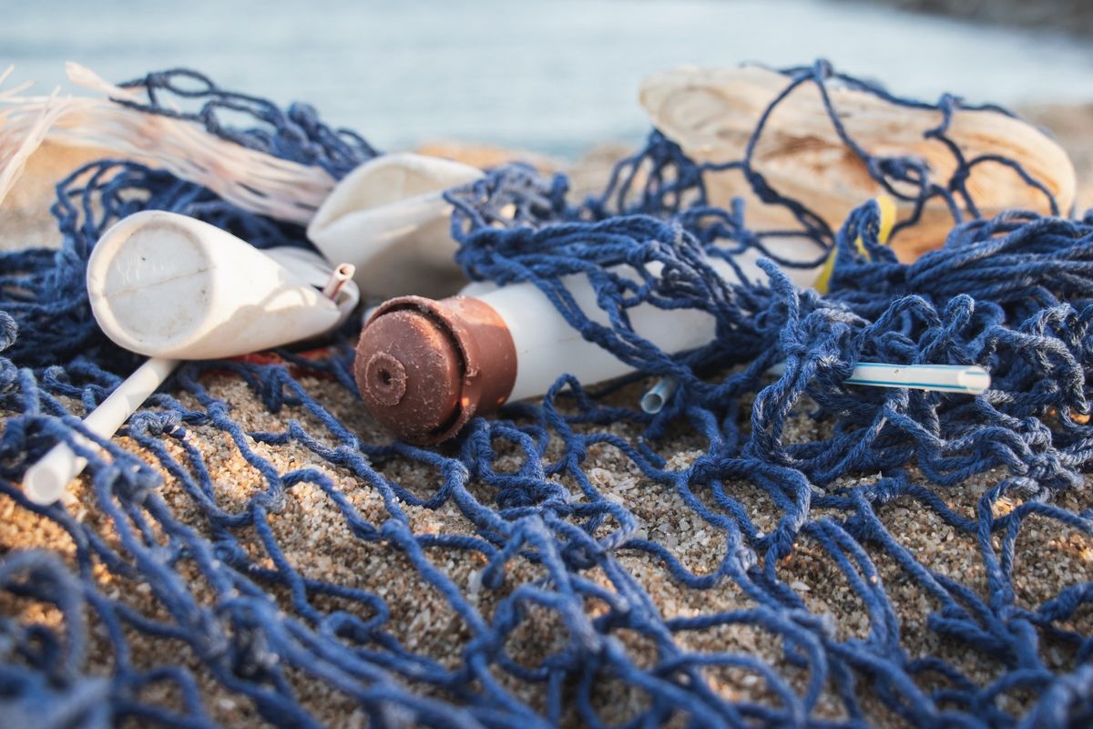 砂浜に打ち上げられた漁網に絡まったプラスチックごみ