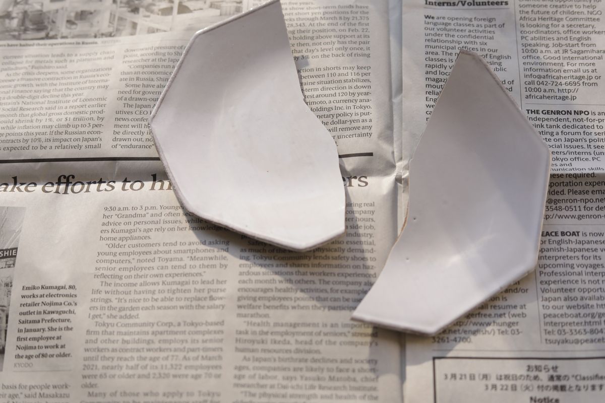 新聞の上に載った割れた皿