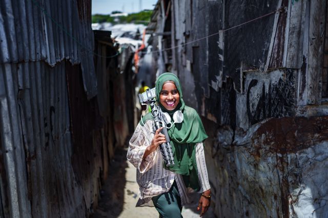カメラの脚立を持つ笑顔のソマリアの女性ジャーナリスト