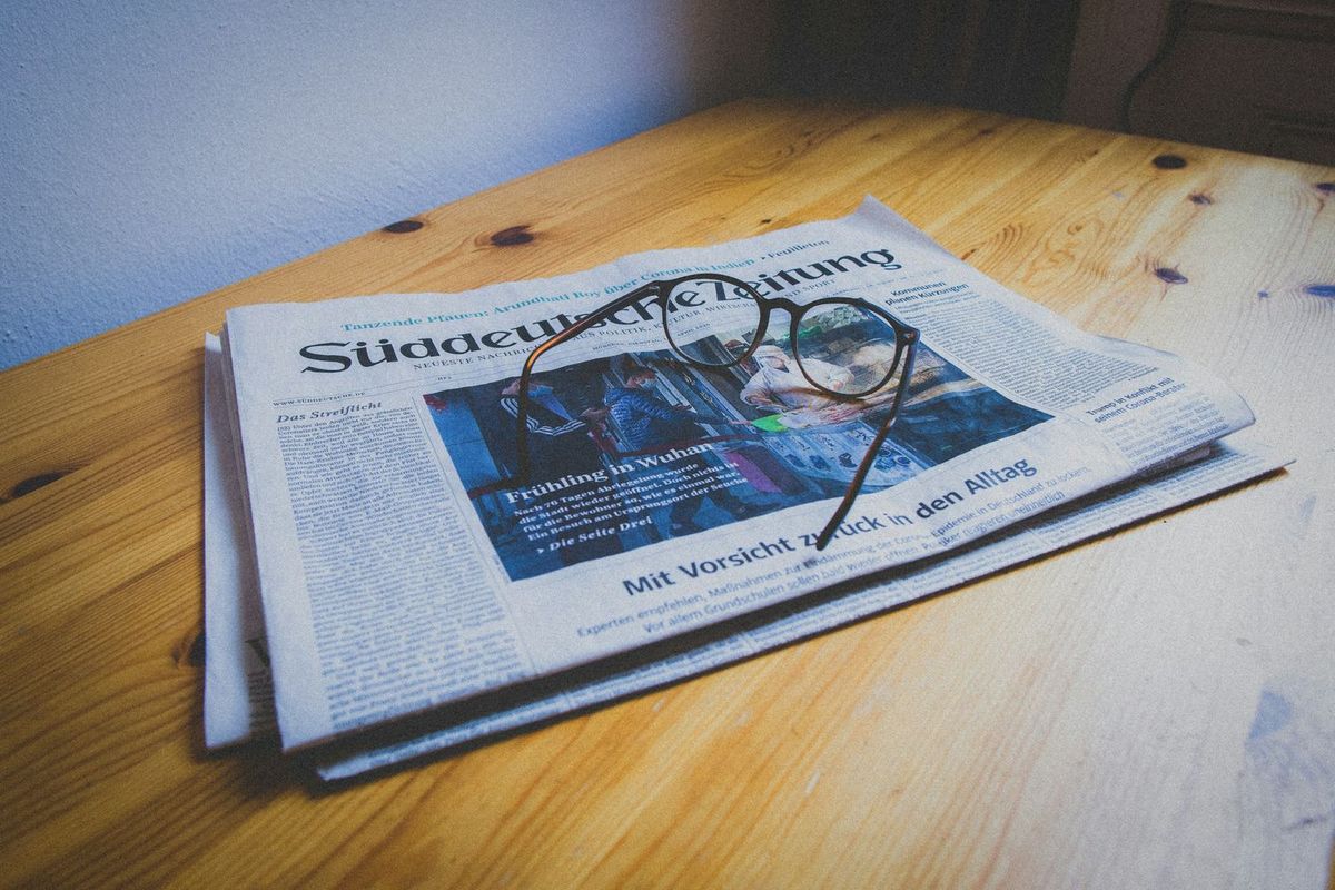 テーブルに置かれた英字新聞と眼鏡