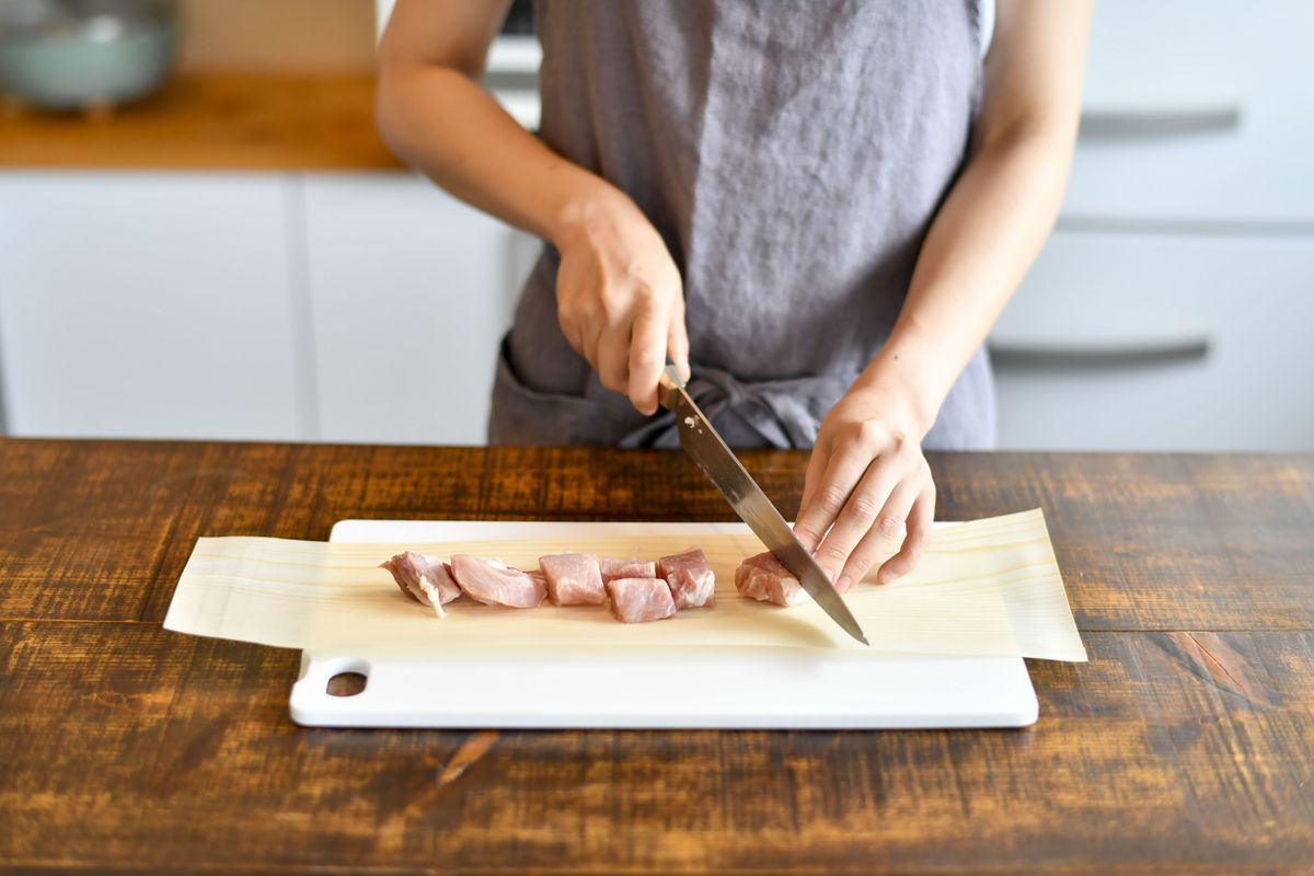 経木を敷いて肉を切っている