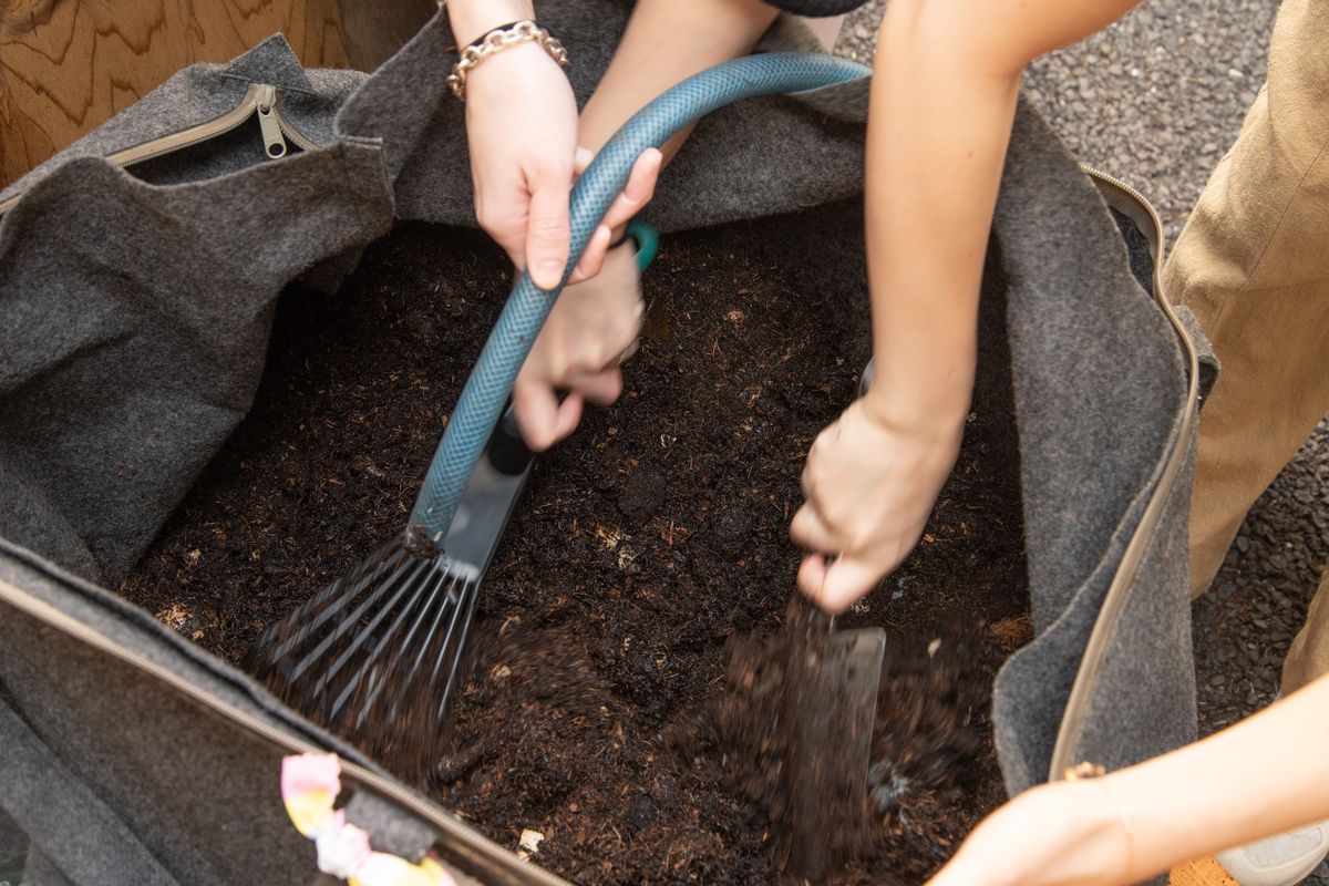 堆肥に水をやり耕すように土を混ぜていく