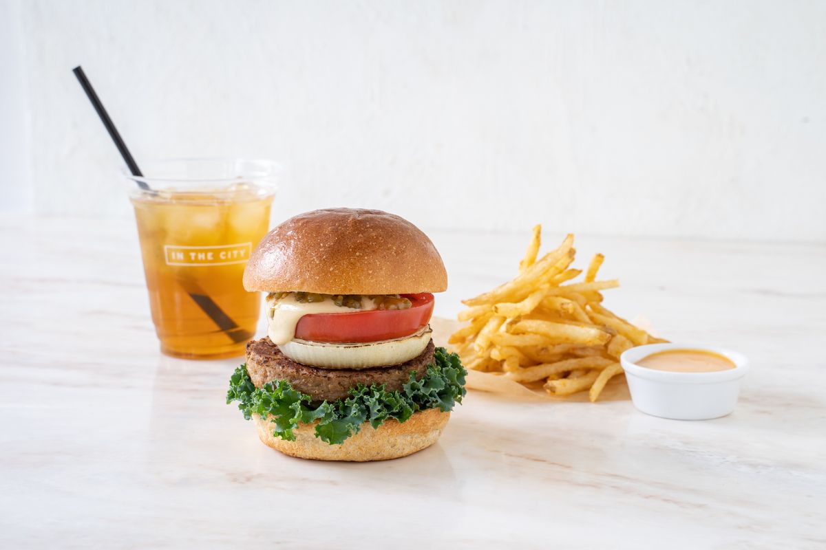 ヴィーガンバーガー、ジュース、ポテトフライが置かれた白地の写真