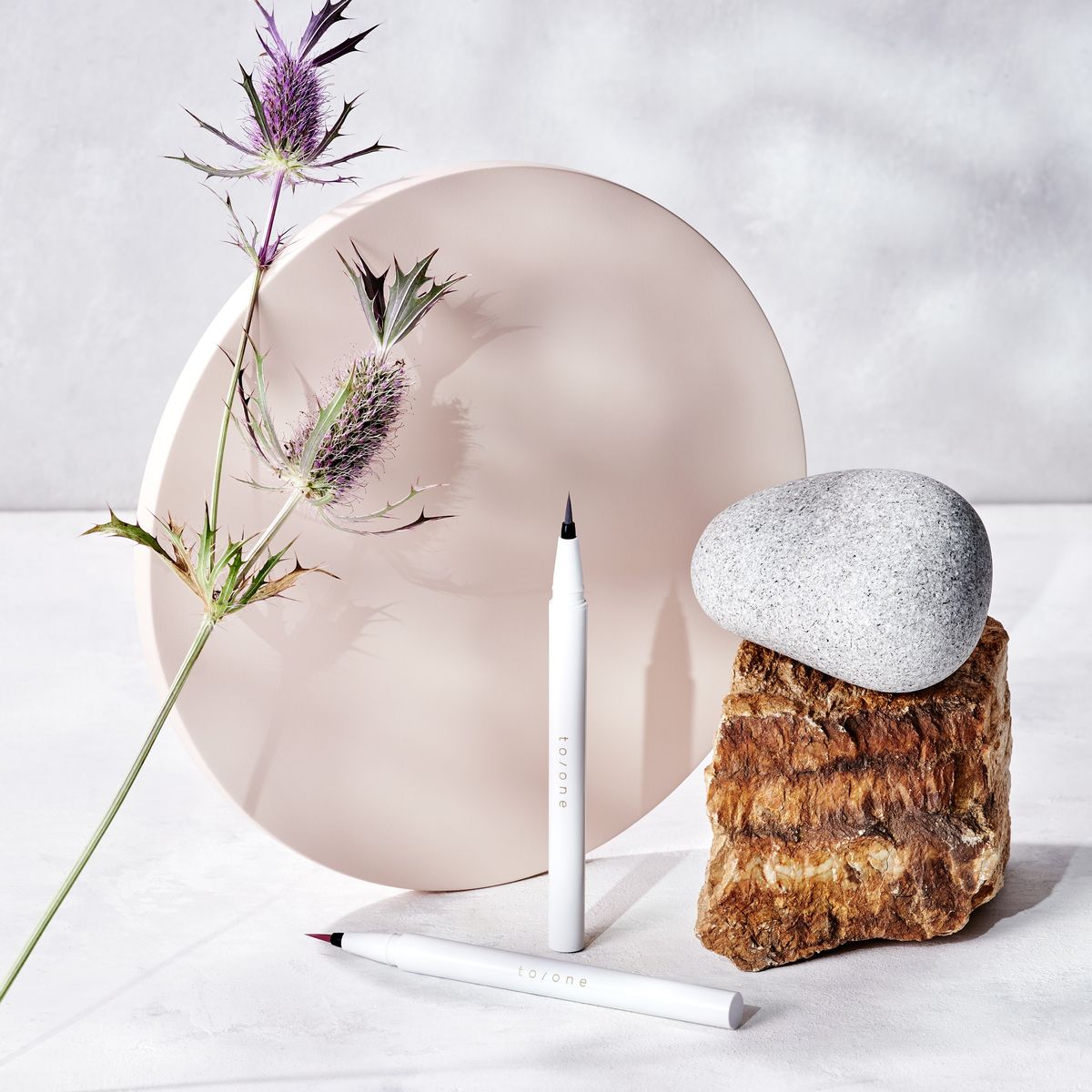 「トーン リキッドアイライナー」、花、石を並べた写真