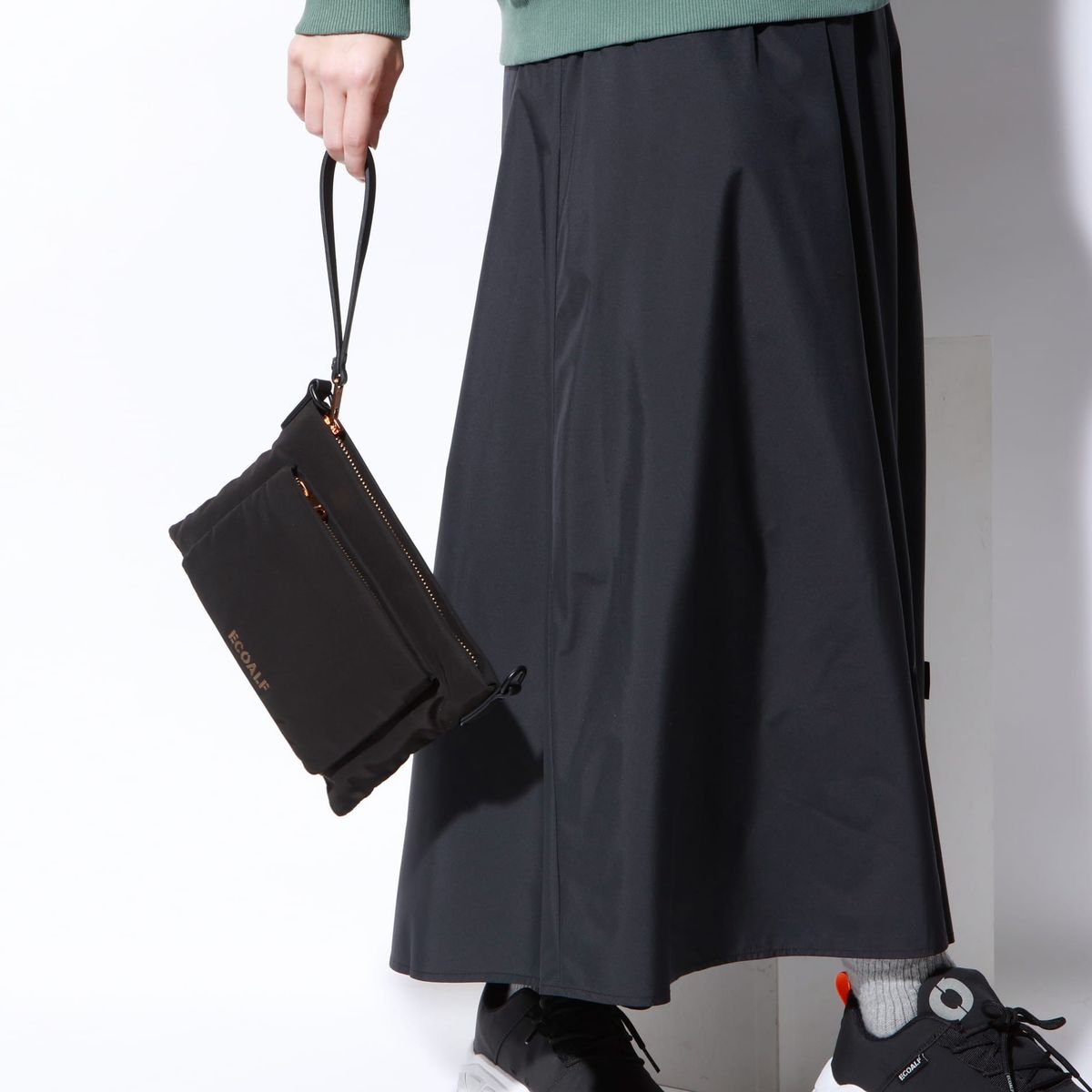 MID FLAT マルチ クラッチバッグを持った人物