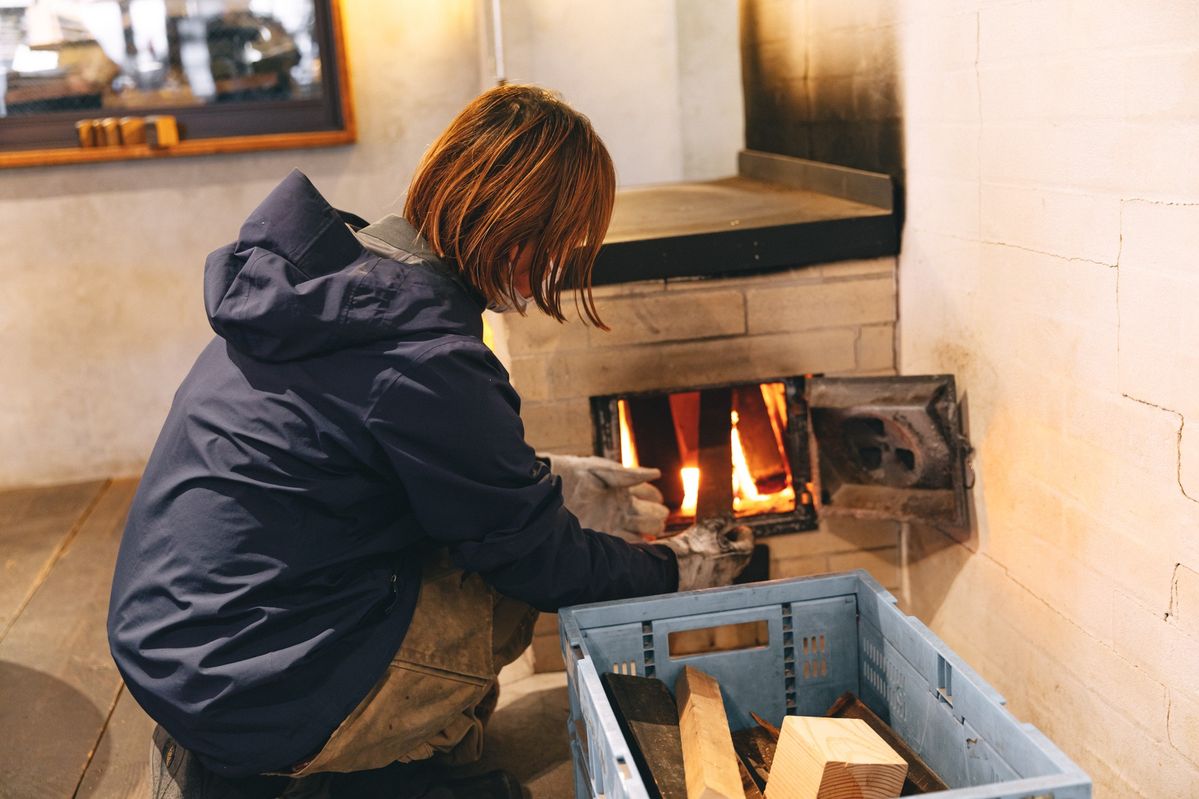 ストーブに薪をくべる女性